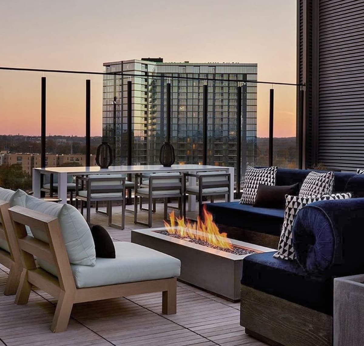 Image of firepit, surrounded by cozy couches on city rooftop at dusk