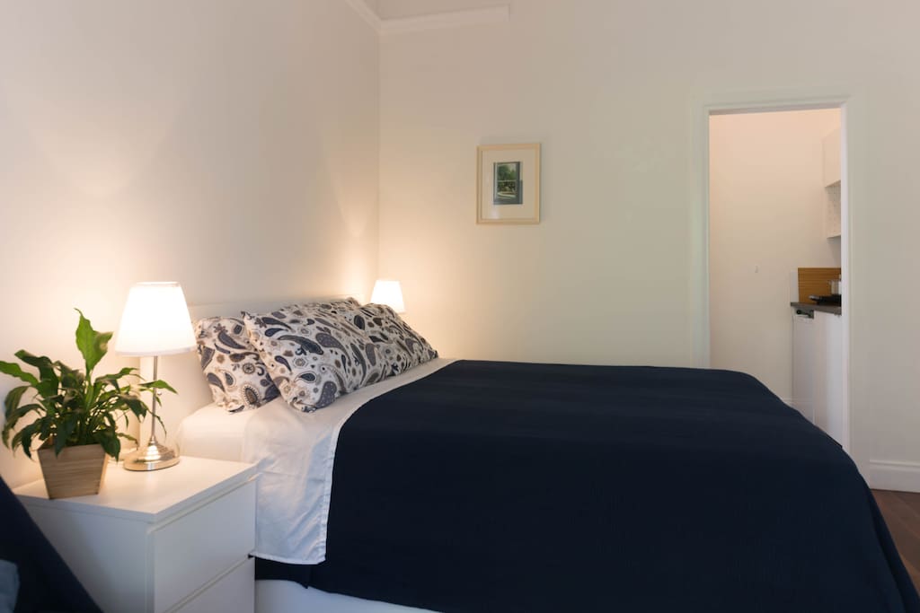 Comfortable queen size bed. doorway leading to kitchenette