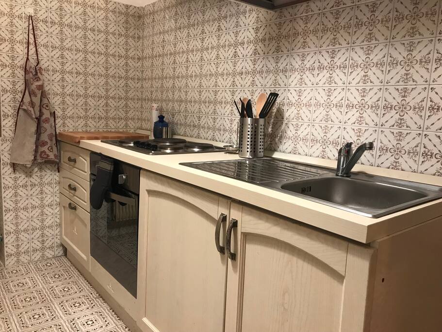 La cucina al piano superiore, fornita di piano cottura, forno, frigo, microonde, piatti, pentole, mestoli, posate, bicchieri..