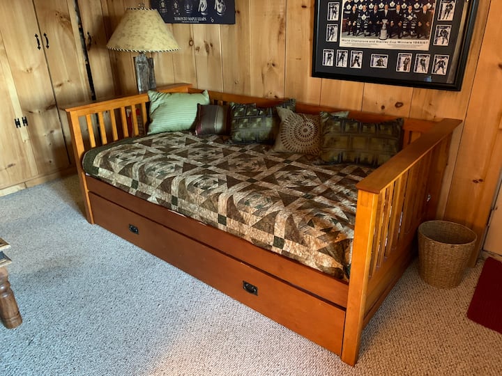 Este sofá cama tiene una cama nido debajo para dormir 2. Se ubica en el nivel inferior de la cabaña principal, junto a la segunda sala de estar.