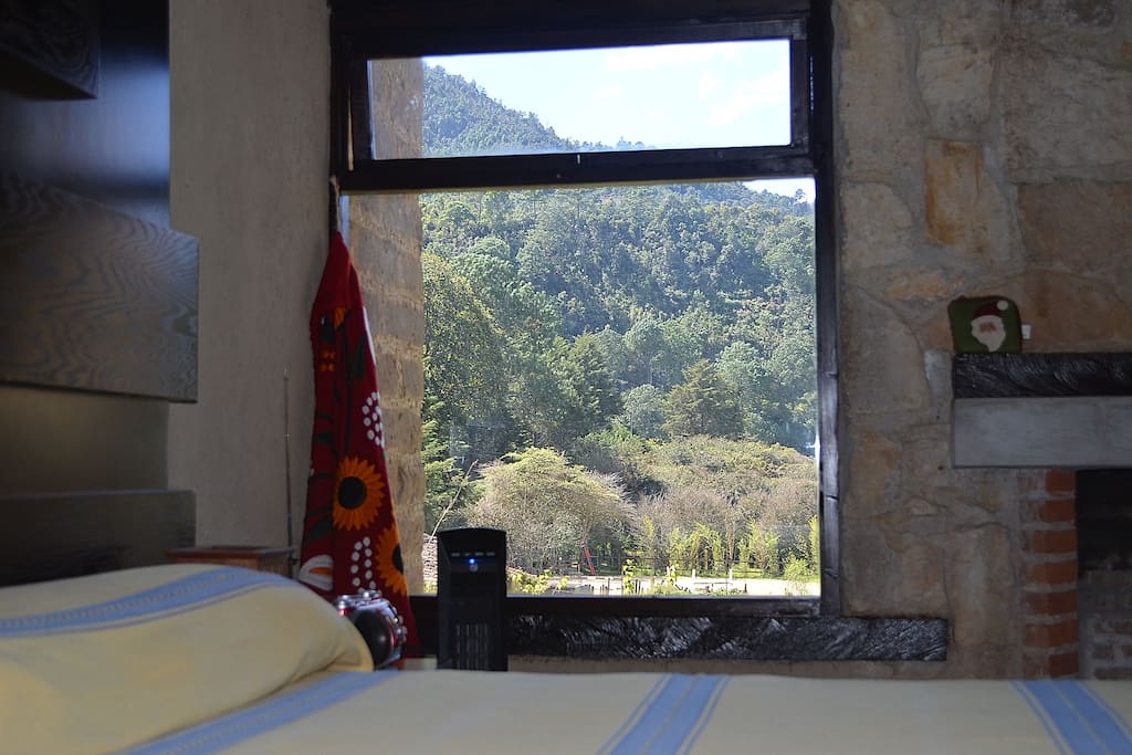 Recamara principal con chimenea y calentador eléctrico. Ventana hacia el jardín y la montaña.