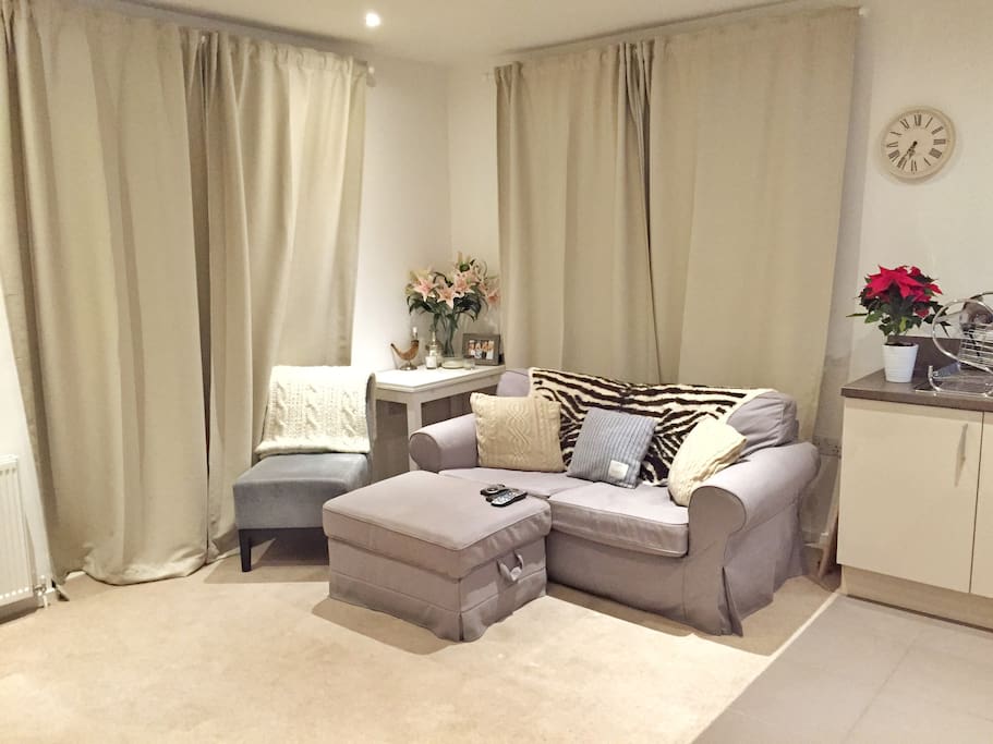 Bright, airy living room, with a 2 seater sofa, foot stool and extra chair. Floor to ceiling windows