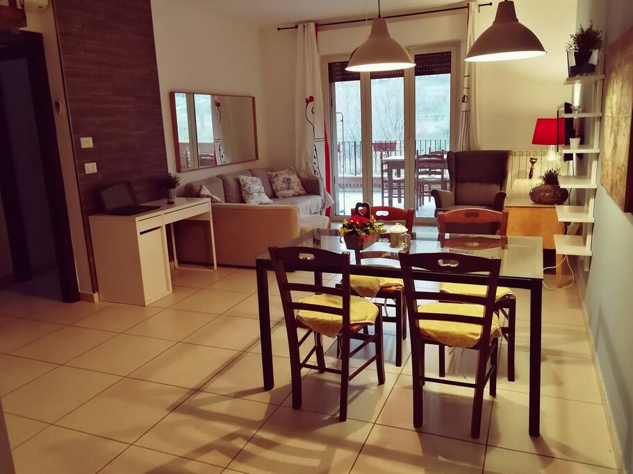 Salone e zona relax con scrivania e cucina a vista.