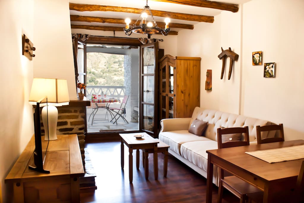 Zona de estar con chimenea, terraza y vistas a la sierra.