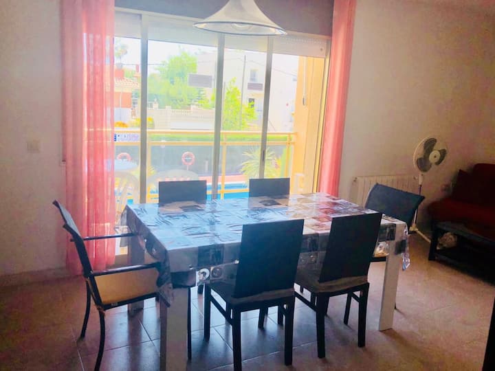 Salón comedor con vistas al jardín ya la piscina. Mesa para 6 personas y sofá cama.