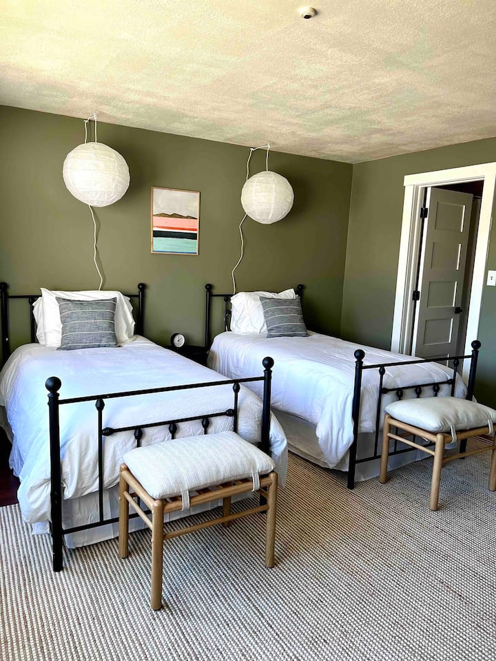 - Dhomë gjumi dyshe elegante me mure të buta jeshile dhe ndriçim modern  
- E përkryer për fëmijët ose miqtë me shtroja të rehatshme dhe atmosferë të qetë  
- Dizajni i qetë dhe tonet e buta krijojnë një hapësirë të qetë dhe çlodhëse  