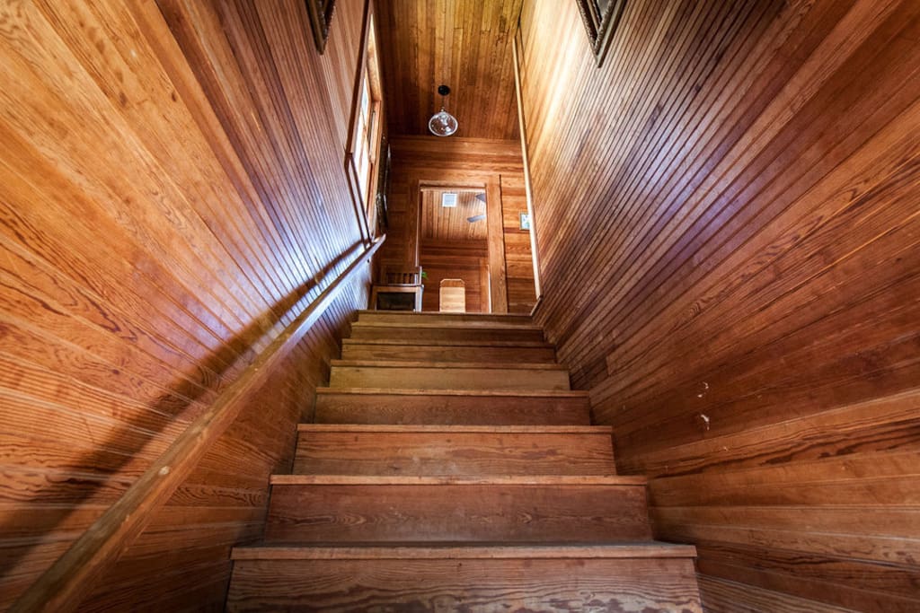 The stairwell in the carriage house has a handrail. Bead-board covers the walls and ceilings, and the floors are long leaf pine.
