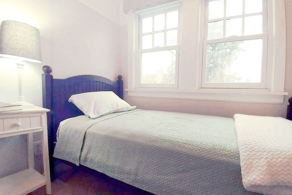 Third bedroom features a cozy twin bed and reading chair