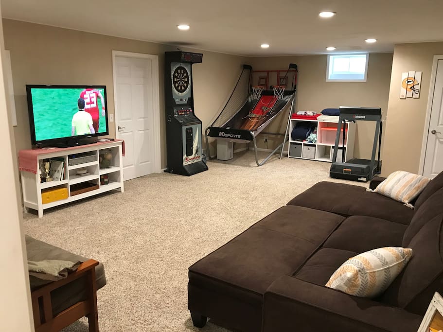 Lower level room with working treadmill, bar-style dartboard, and basketball game.