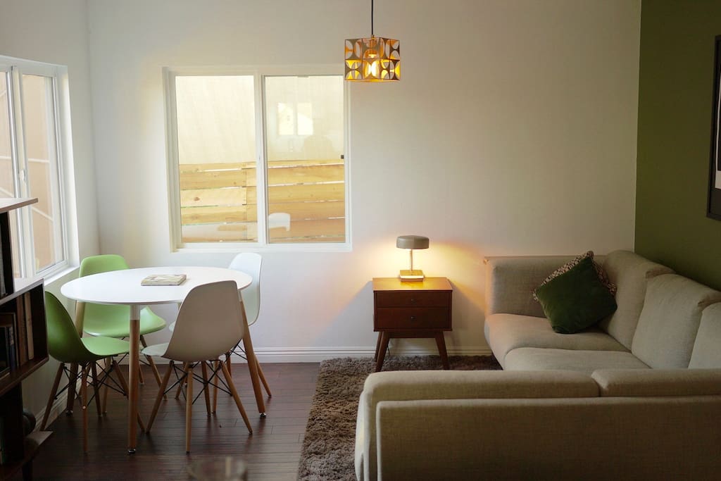 Living area opposite the kitchen with huge comfy sofa, dining table with garden view, art book collection and TV