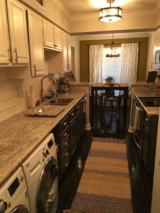 Galley kitchen includes stainless steel appliances and front loading washer/dryer.