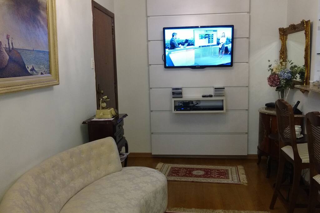 sala de estar com sofá , TV e duas cadeiras decorativas