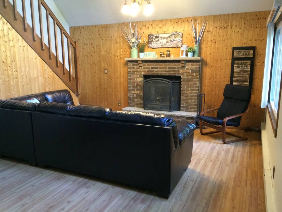 Living Room. Open floor plan, vaulted ceilings, leather sofa and wood burning fireplace.