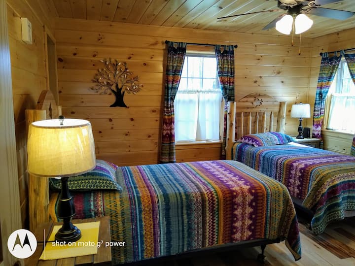 Colorful Master bedroom with both twin bedspreads, curtains and shower curtain to full bathroom with double sinks.
