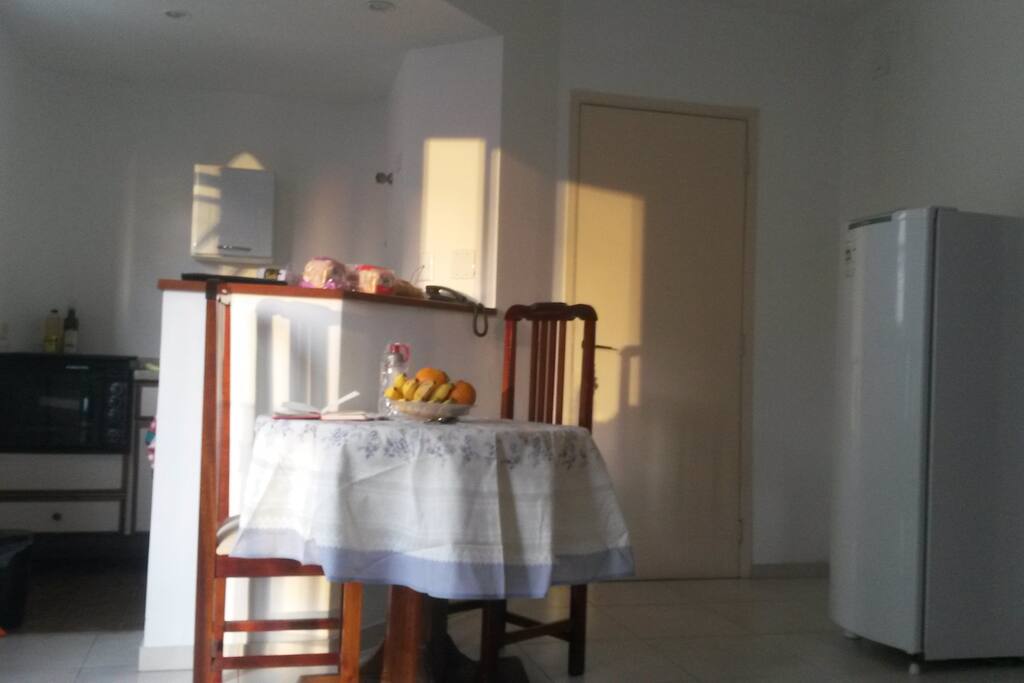 Dinners table with the kitchen in the back in the daylight.