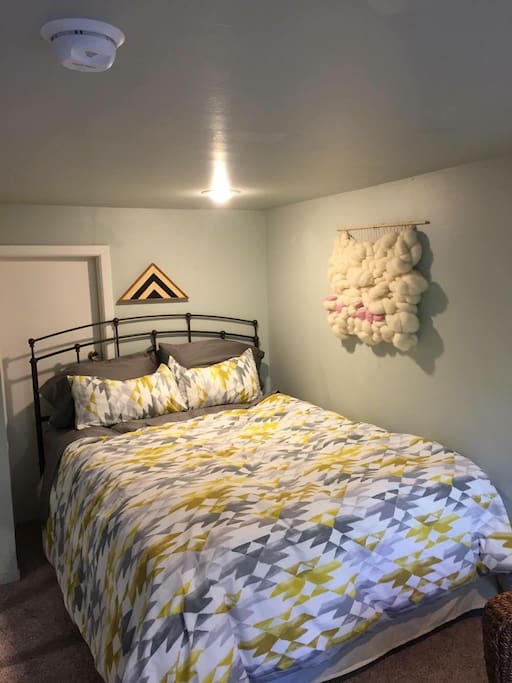 This comfortable bed is queen size and a wall furnace keeps the apartment warm and cozy.
