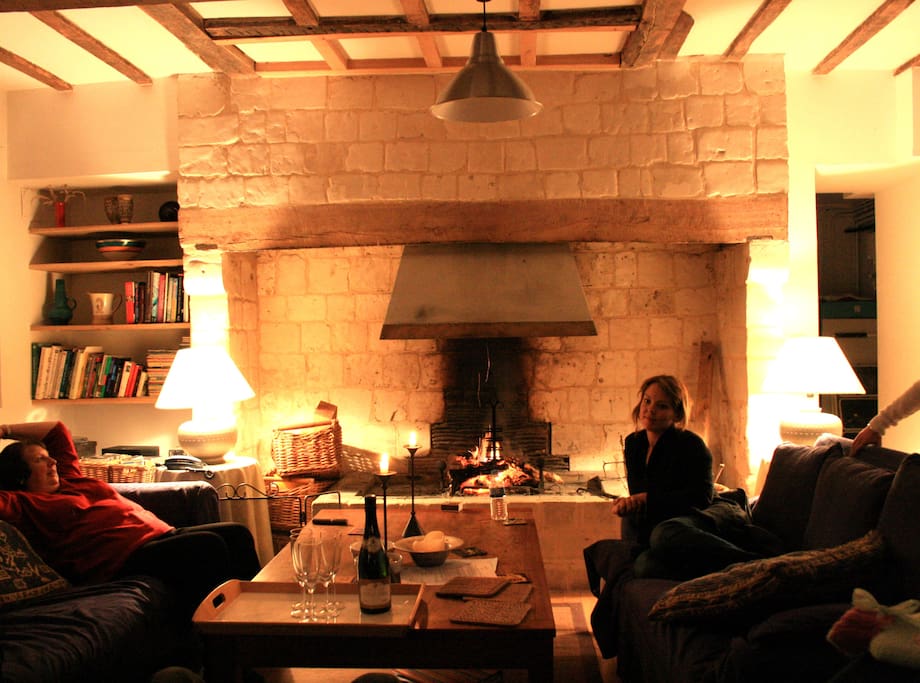Large living room with 3 comfortable sofas, beams on ceiling and big open log fire