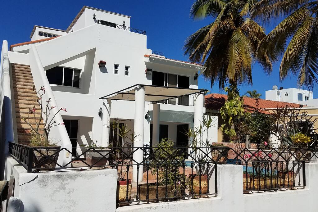 Vista por el lado de atrás de la casa que muestra las escaleras para entrar al departamento. Entrada independiente.