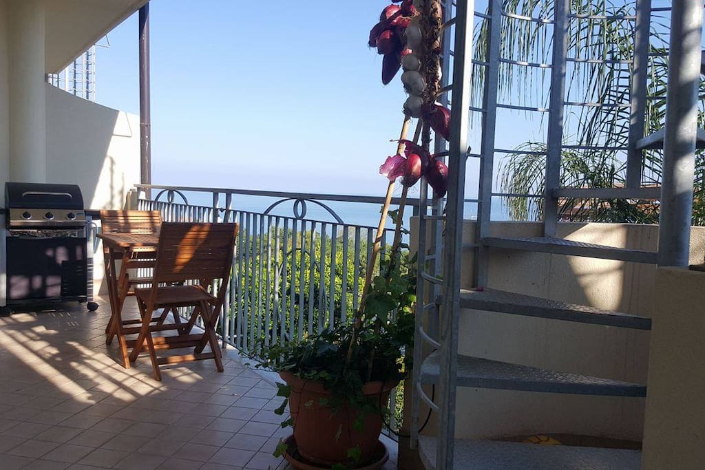 entrance to the apartment and balcony with table seating for 2 people. Barbecue. Staircase leads up to the sun terrace on the roof.