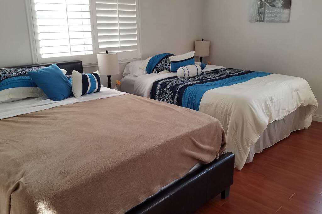 Spacious Mid-sized bedroom with hardwood-like laminate flooring and wooden shutters. 2 Queen beds that fit up to 4 people