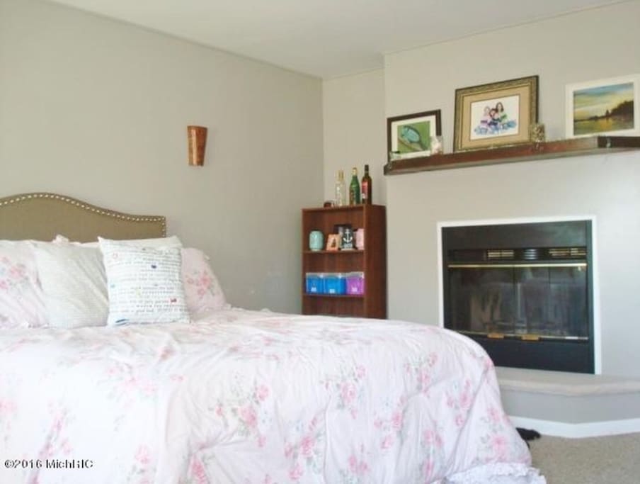 Master bedroom with new queen bed and dresser. The fireplace is two sided into the family room.