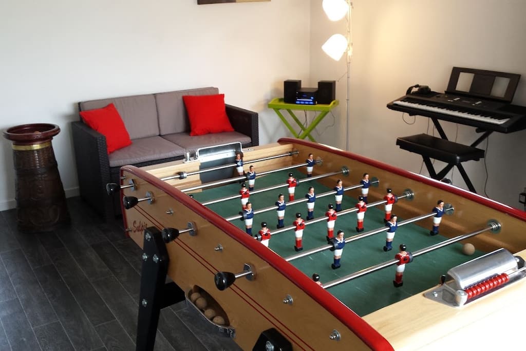 Espace loisir : baby-foot, piano, enceinte, canapé