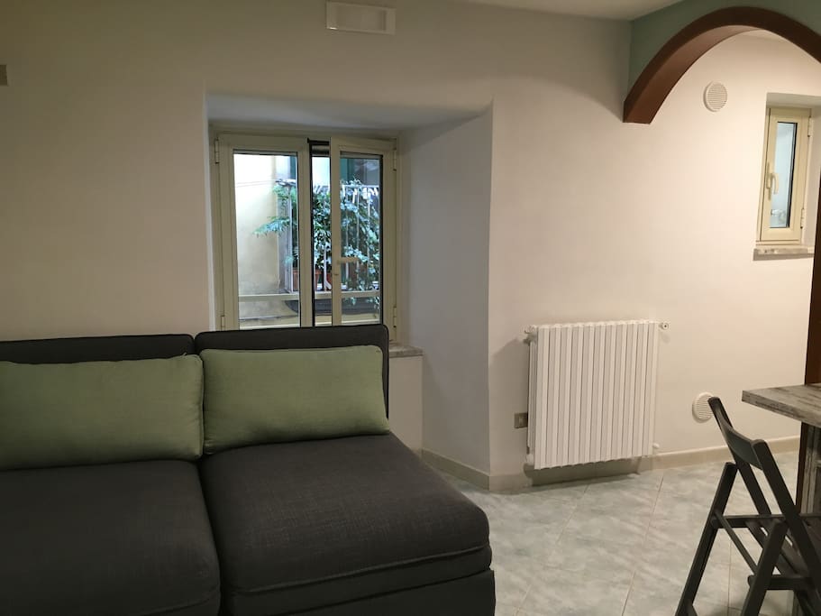 Soggiorno con divani letto aggiuntivi. Apertura singola o matrimoniale. Finestra su vicolo laterale.