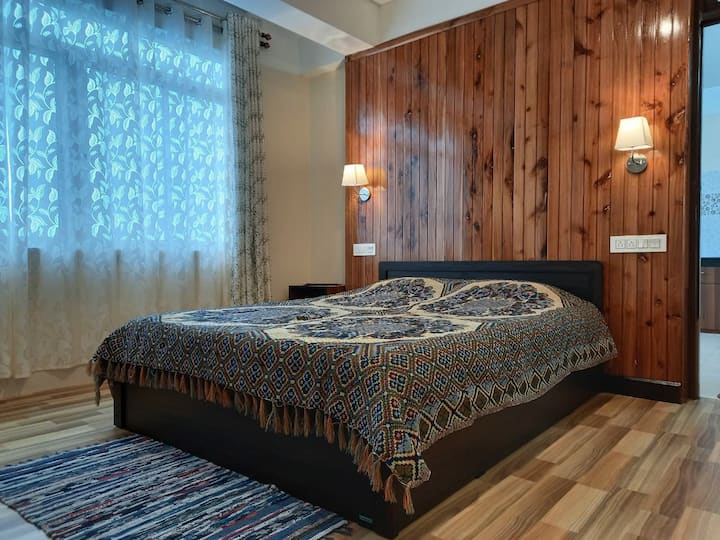 The Master Bedroom is spacious & has an ensuite bathroom. The wooden panelling adds warmth to the space & makes it cosy. The windows overlook the view of the valleys and tea gardens.