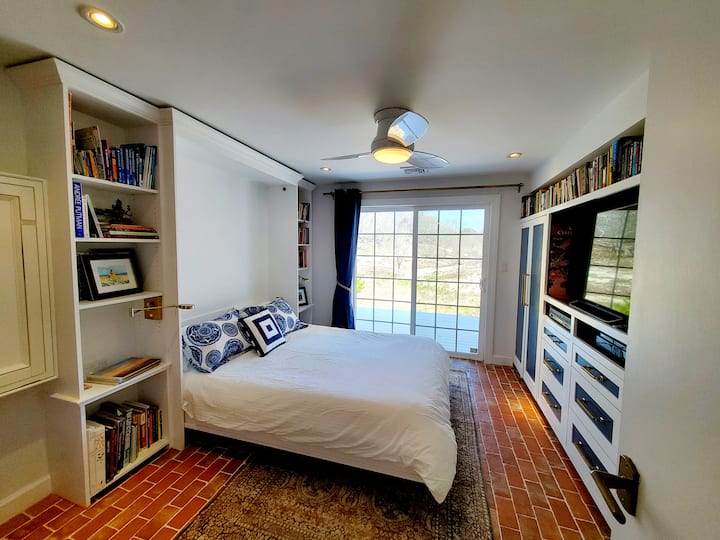 dormitorio con cama tamaño queen, televisión inteligente y cocina pequeña