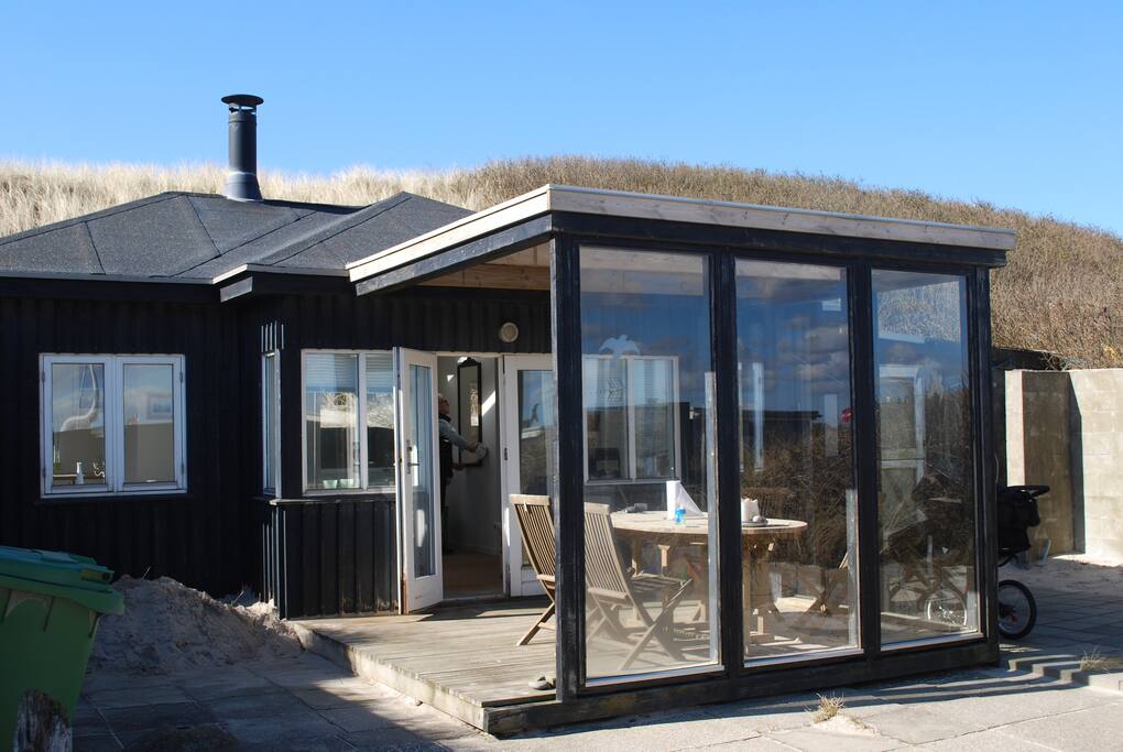 Huset udefra med havet og stranden lige på den anden side af klitten