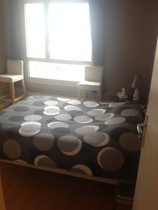 Chambre N°1 calme qui donne sur un parc arboré de la copropriété, lit double, table de nuit, lampe de chevet, commode et chaises