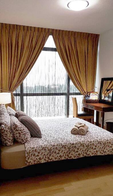 Well Furnished Master Bedroom with String & Night Curtains, Queen Divan Bed with Beddings, Bar Fridge, Table Lamp, Table, Chair, Table Light, Mirror etc.