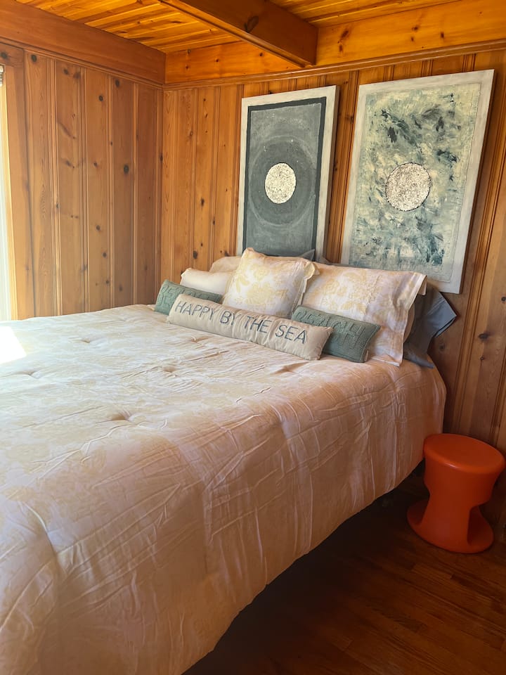 Dormitorio en la planta superior con cama tamaño queen, vestidor, silla y armario.