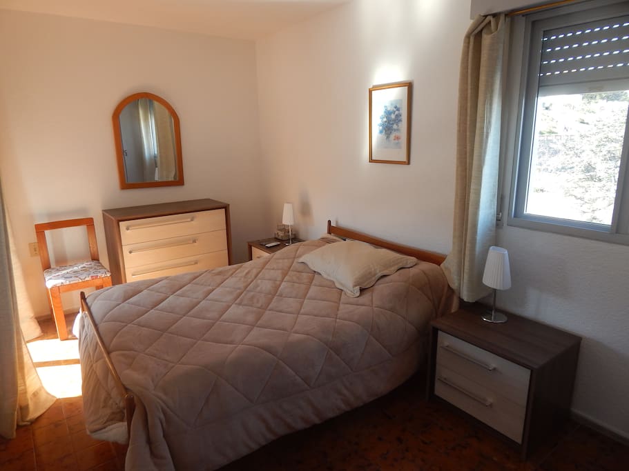 dormitorio con una ventana hacia el puerto y un ventanal hacia el balcón.