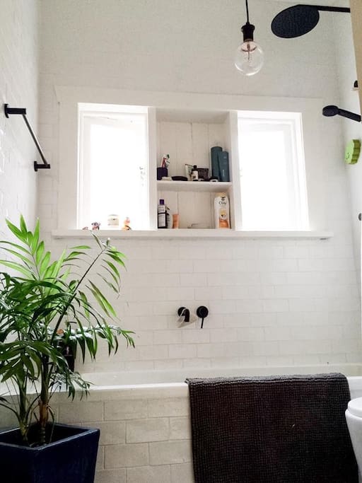 Brand new subway tiled chic bathroom with bath, tall ceiling, hairdryer, hair straightener.