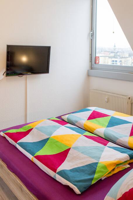 Blick vom Bett (Schlafzimmer) auf den Fernseher und das große Tageslichtfenster.