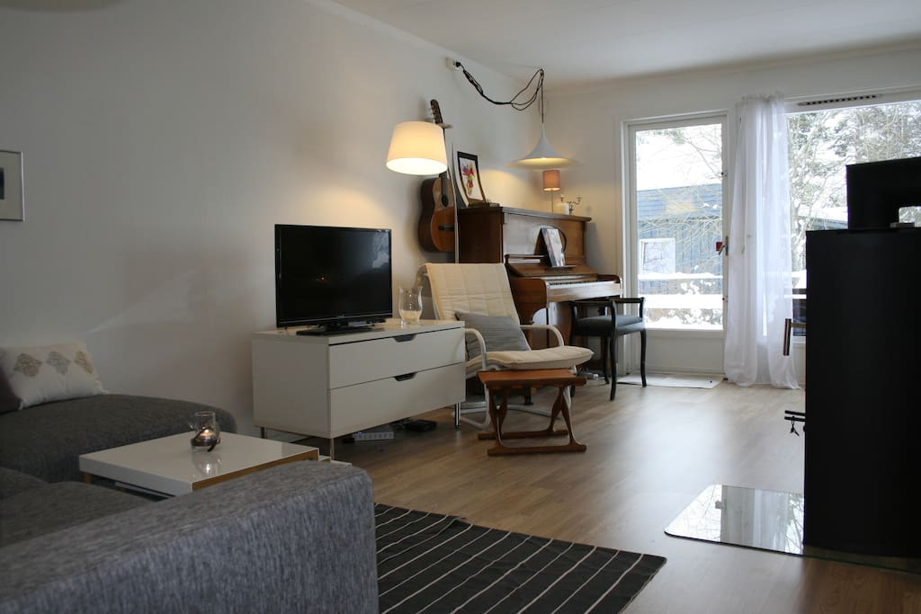Light living room with comfy couch, fireplace, cabel-tv and piano.