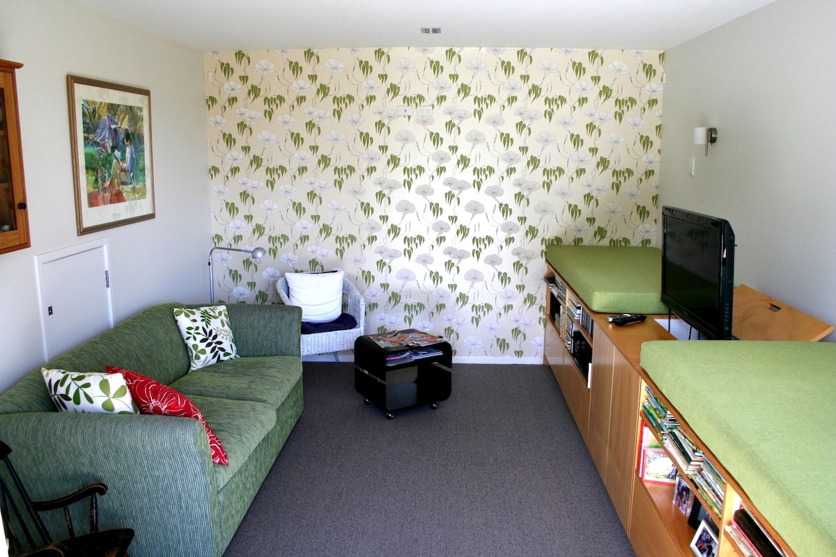 Chumba cha "Snug" kina droo zilizojaa midoli na vitabu vya watoto na ufikiaji wa moja kwa moja wa nje.  Jukwaa la kulala linafaa watoto au watu wazima na sofa hukunjwa kitandani.  Magodoro ya sakafu kwenye kabati nyuma ya sofa. 

