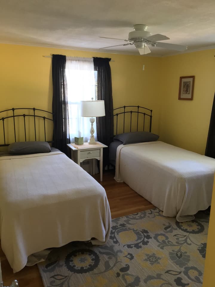 חדר שינה עם שתי מיטות זוגיות ארוכות במיוחד ומאוורר תקרה. בכל חדר שינה יש מזגן מפוצל. 