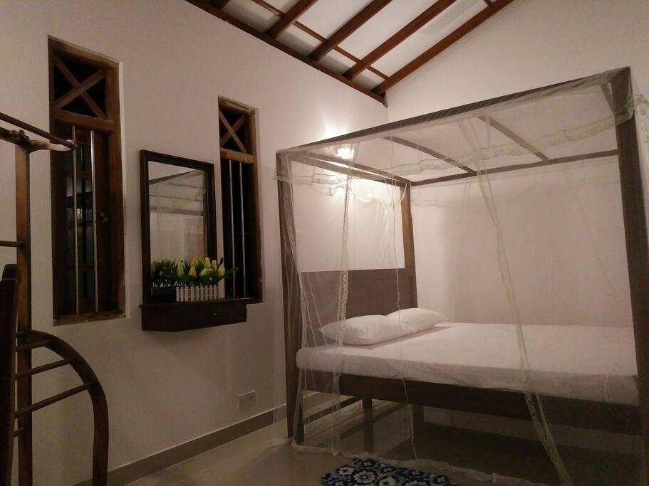 Large balcony view bed room with sri Lankan style queen size bed/clothes rack/mirror and drawer/table and chair
