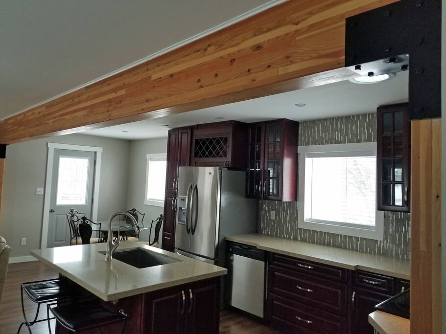Kitchen island has bar stools, there is lots of natural light and big windows in this home.