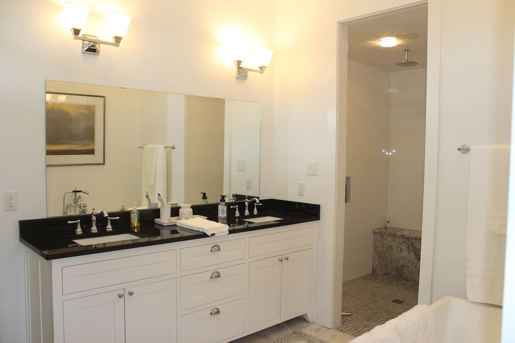 Double vanity and walk-in shower with bench and separate toilet area