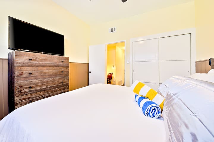 Dormitorio #4: TV de pantalla grande con control remoto con cama tamaño queen ajustable y cómoda y ventilador de techo.