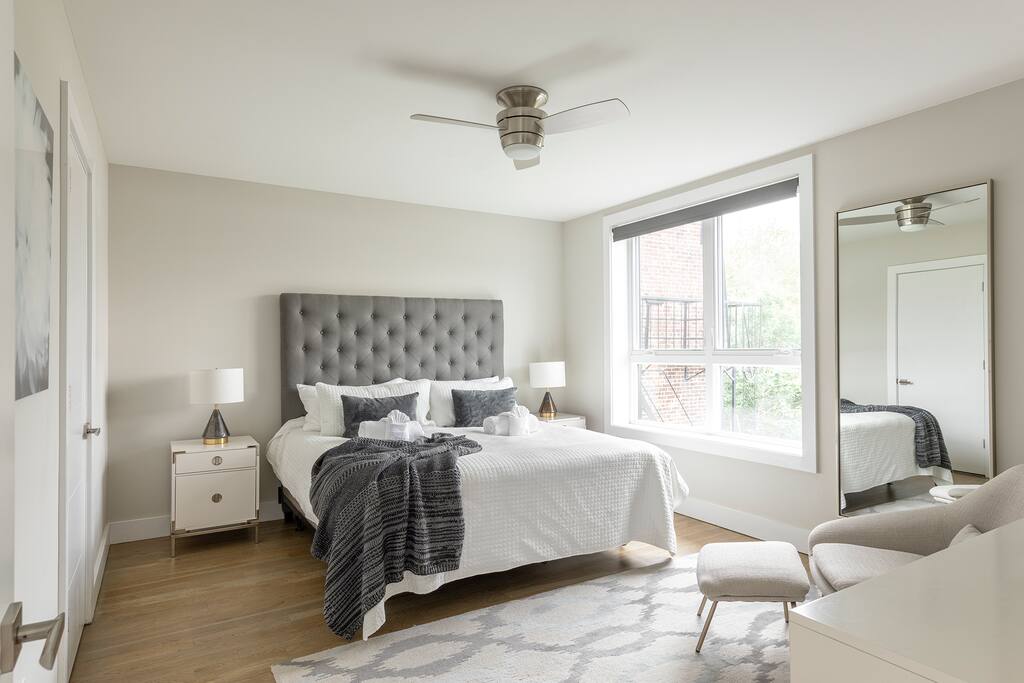 The king-size bed in the expansive master suite is layered with crisp, white linens, a down comforter and coverlet tucked into an elegant high-profile, tufted headboard.