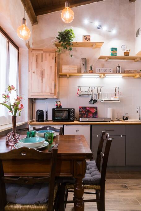 Cucina con tavolo allungabile, piastra a induzione, fornetto, macchina per il caffè, bollitore, tostapane, lavatrice e frigorifero | Kitchen with table (adjustable, up to 4 people), induction, electric oven, coffee machine, washing machine and fridge.