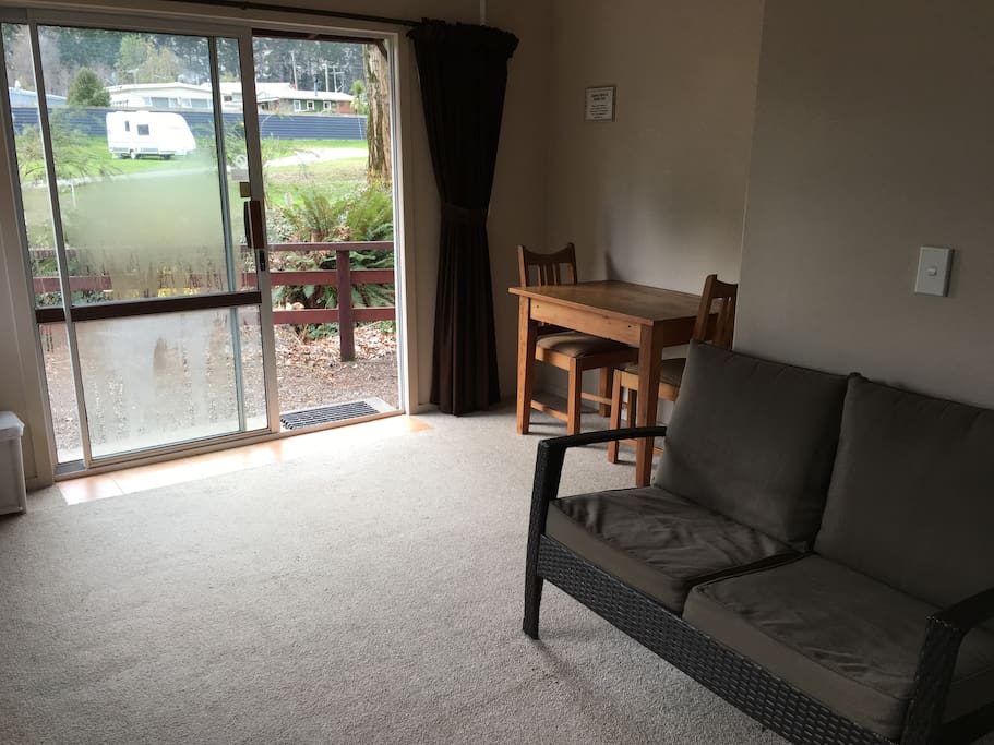 Open plan studio, sofa chair, dining table. Creek just outside the front entrance.
