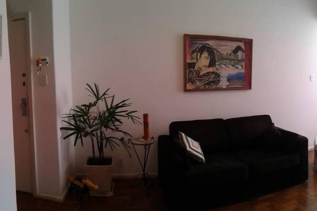Sala com sofá cama estilo americano, tv, poltrona de massagem e ar condicionado