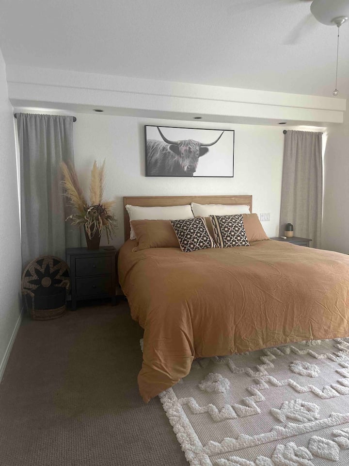 Cama tamaño king en el dormitorio principal con puertas corredizas de vidrio que conducen a vistas exteriores. Cortinas opacas y vestidor. Bañera de hidromasaje en el dormitorio principal privado con ducha e inodoro. La habitación tiene ventilador de techo con TV.