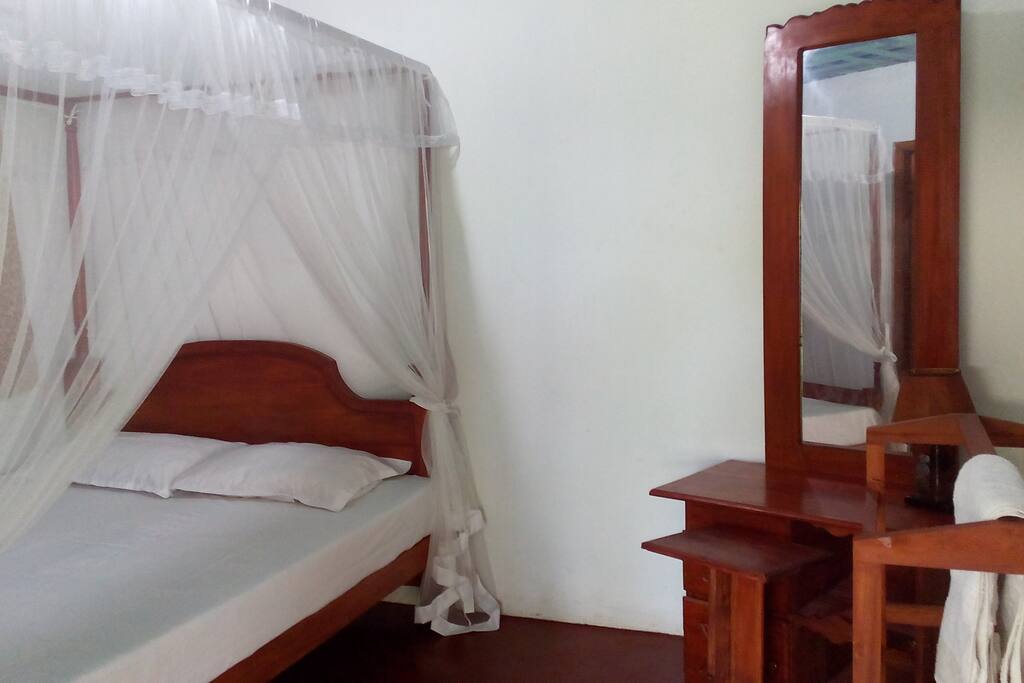 Double bed with mosquito net & vanity.
