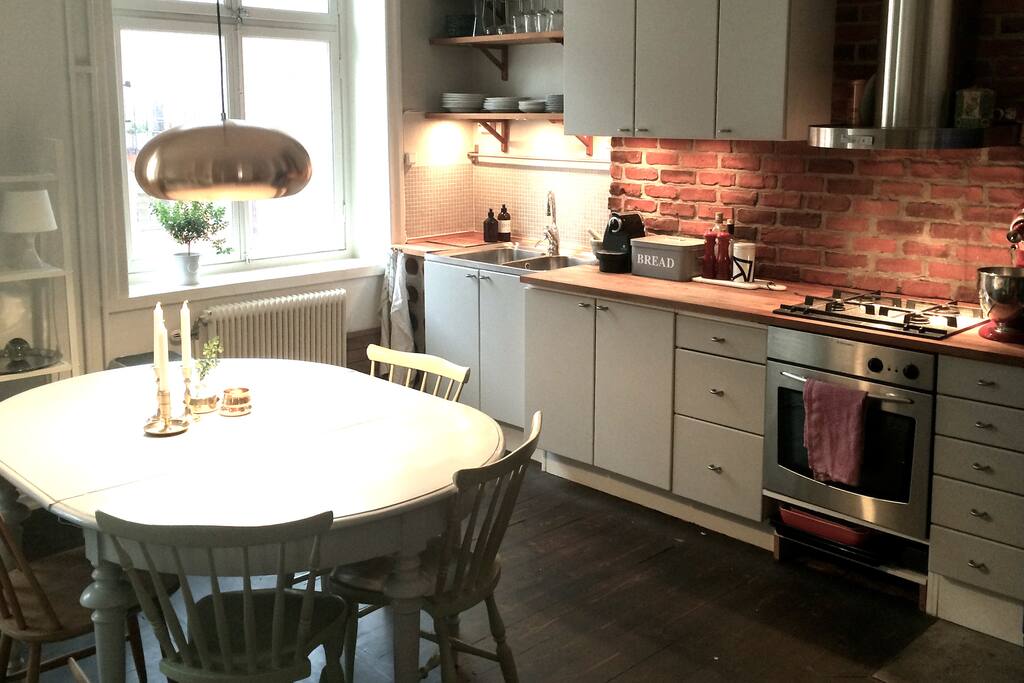 Big dining table in connection to fully equipped kitschen